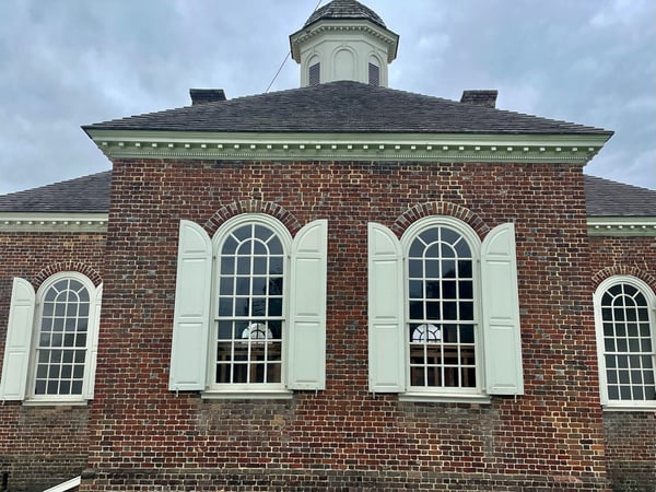 A Colonial era building with elliptical shutters flanking Palladian windows
