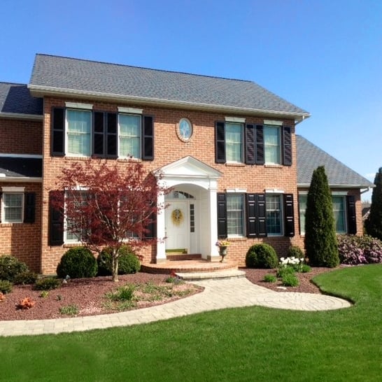 Blakc panel and louver shutters on red brick house front angled social edit