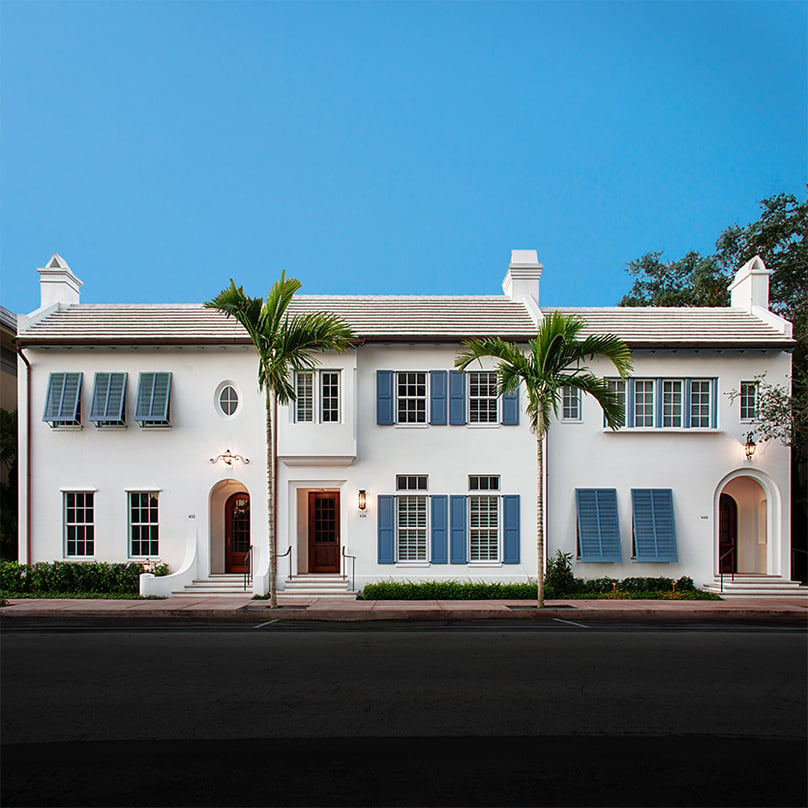 Blue panel and bermuda shutters white stucco house front social edit