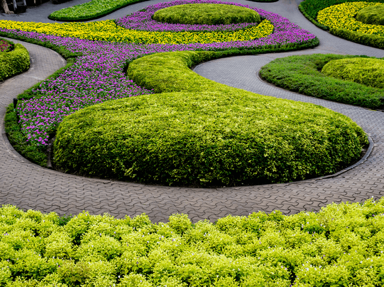 unique pavers style walkway in a swirl design with neatly trimmed landscaping featuring shrubbery and flowers