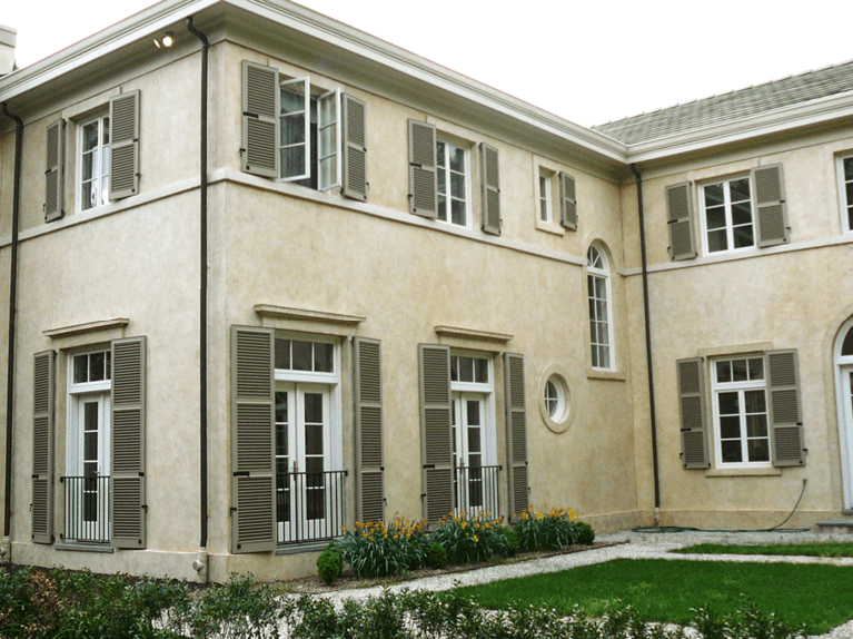 tan stucco home with Timberlane louver shutters finished in a khaki premium finish and functional shutter hardware