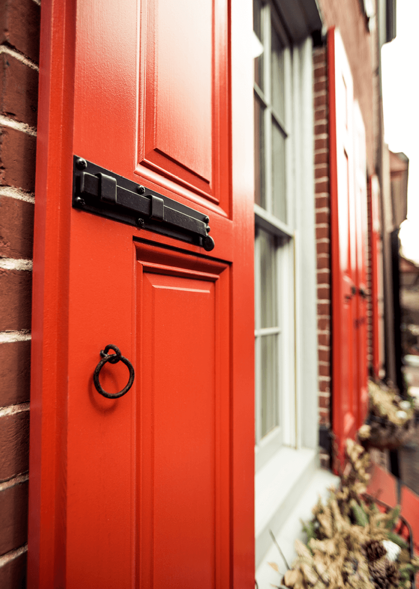 panel shutters with functional hardware on a brick home exterior