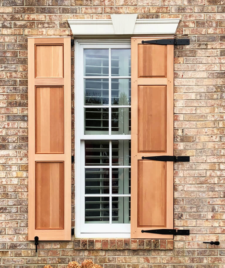 brick home with unfinished wood shutters and functional shutter hardware