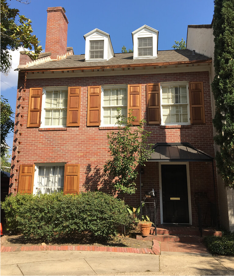 red brick home with unfinished wooden panel shutters