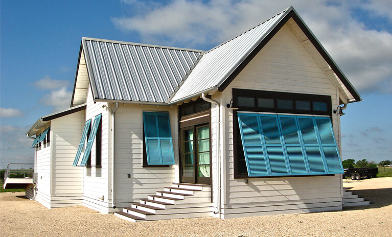 blue topaz hurricane rated bahama shutters on white beach bungalow home