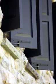 close up of dark blue panel shutters with functioning Hardware on tan stone home