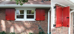 Red bi-fold vertical groove panel shutter on brick home