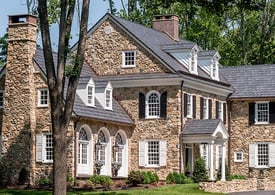 white panel and black louver shutters on tan stone home