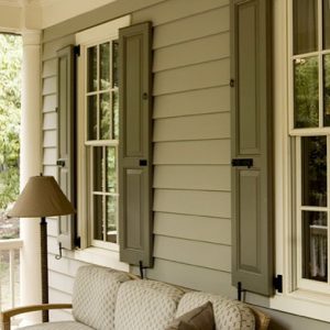 Green panel shutters on green house front porch