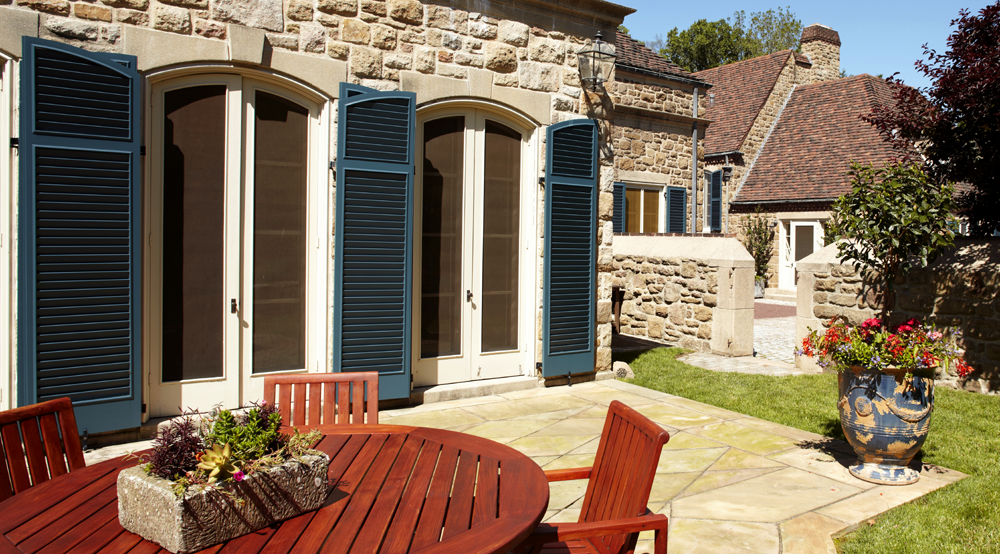 blue Endurian fixed louver shutters with arch tops on sides of doors