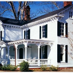 TIMBERLANE'S OPERABLE LOUVER, RADIUS-TOP BLACK SHUTTERS ON A HOUSE WITH WHITE SIDING.