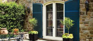 blue fixed louver shutters with arch tops on tan stone home