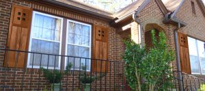 stained wood mission style shutters on brick home