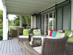 This inviting porch lounge features customized fixed louver shutters mounted on a sliding track to allow privacy, breeze, and a bit of light inside all at the same time.