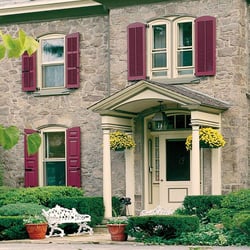 red louver and panel shutters on stone home