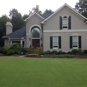 Blue panel shutters with functional hardware on gray stucco home