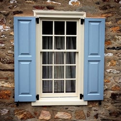 lIGHT BLUE PANEL SHUTTERS ON TAN STONE HOME