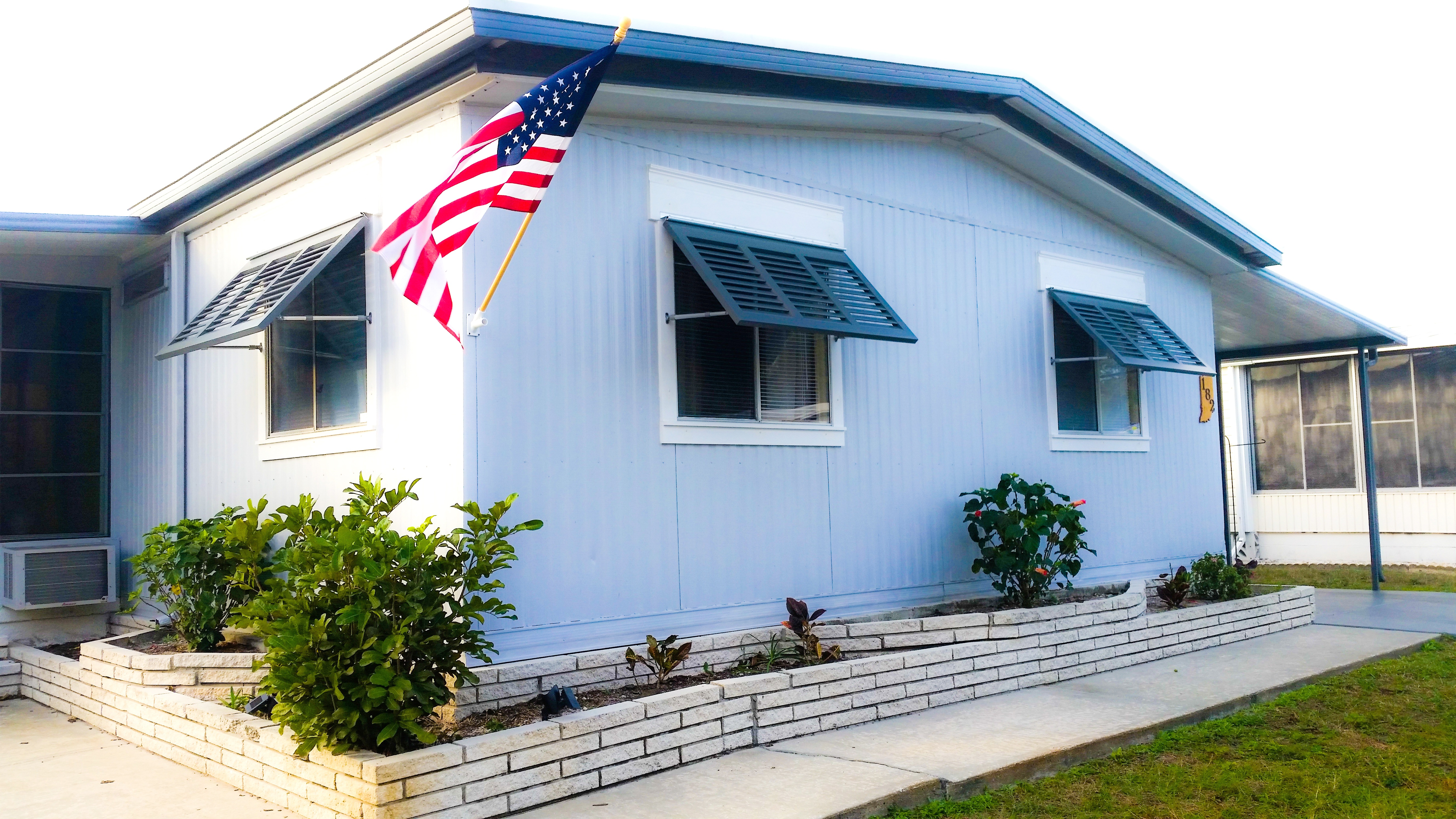 Blue bermuda shutters on light blue home