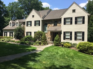 Black panel shutters on white stucco and tan stone home