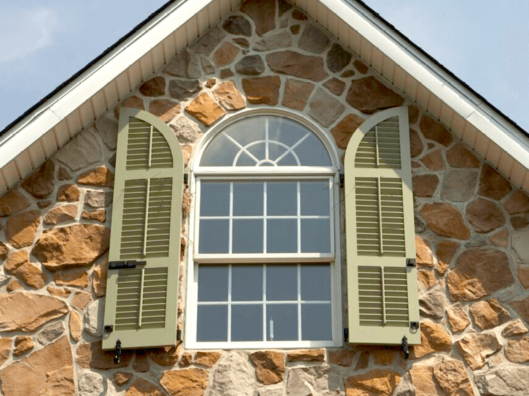 arch top exterior shutters for a stone home