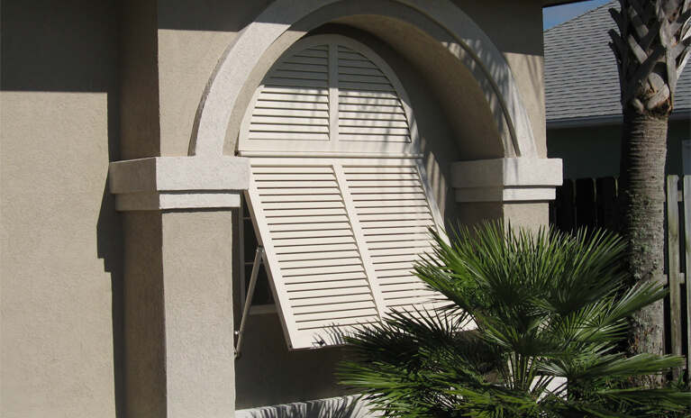 tan home with custom bahama style shutters with tilt rods to control light and airflow