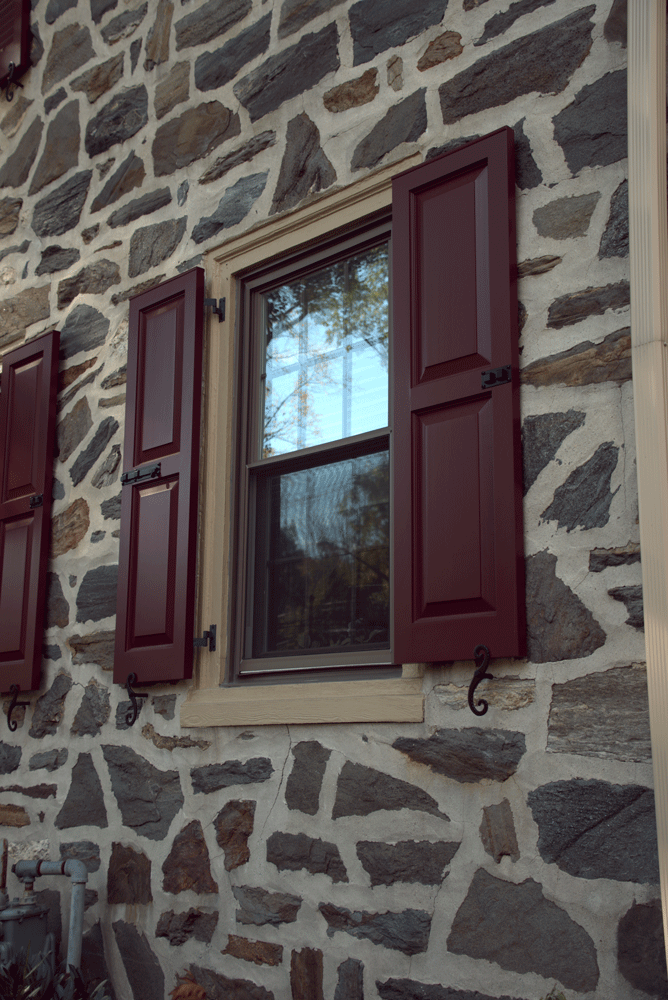 b-Dark-red-panel-shutter-day-gray-stone-house-first-floor-windows-cropped