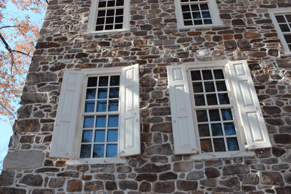 b-White-panel-shutters-brown-gray-stone-house-front-first-floor-windows